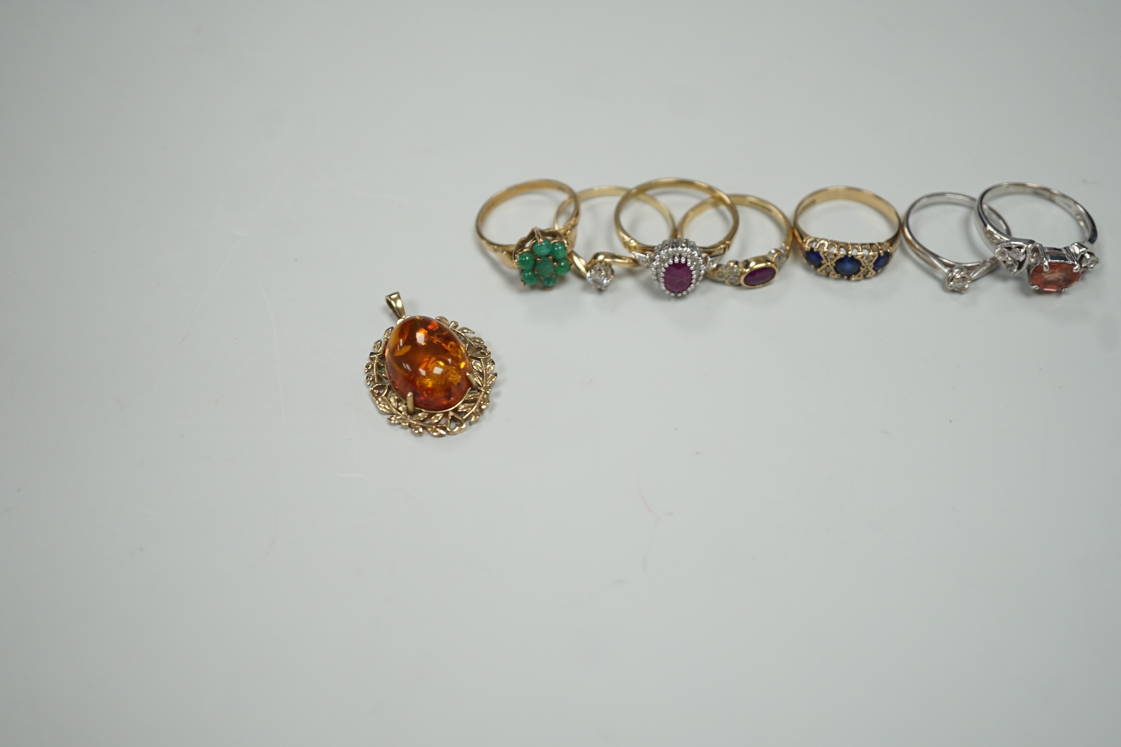 Seven assorted modern 9ct gold and gem set rings, including two solitaire diamond rings, together with a 9ct gold and amber set pendant, gross weight 19.3 grams.